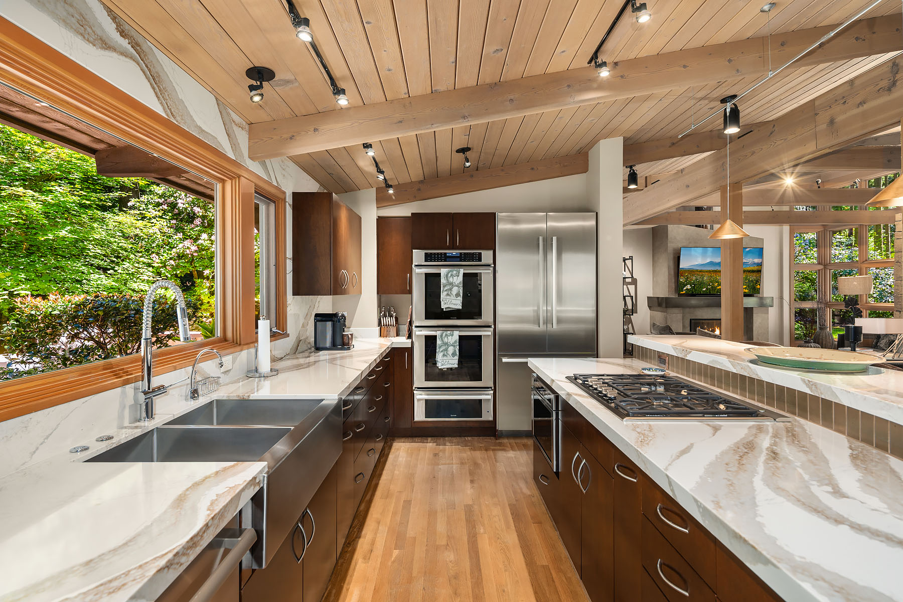 Quartz kitchen with stainless apron sink, double oven, gas cooktop, and exposed cedar beams