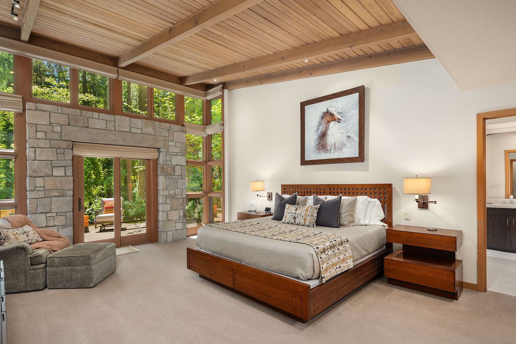 The primary suite with vaulted cedar ceiling, stone fireplace surround, and a slider to the patio